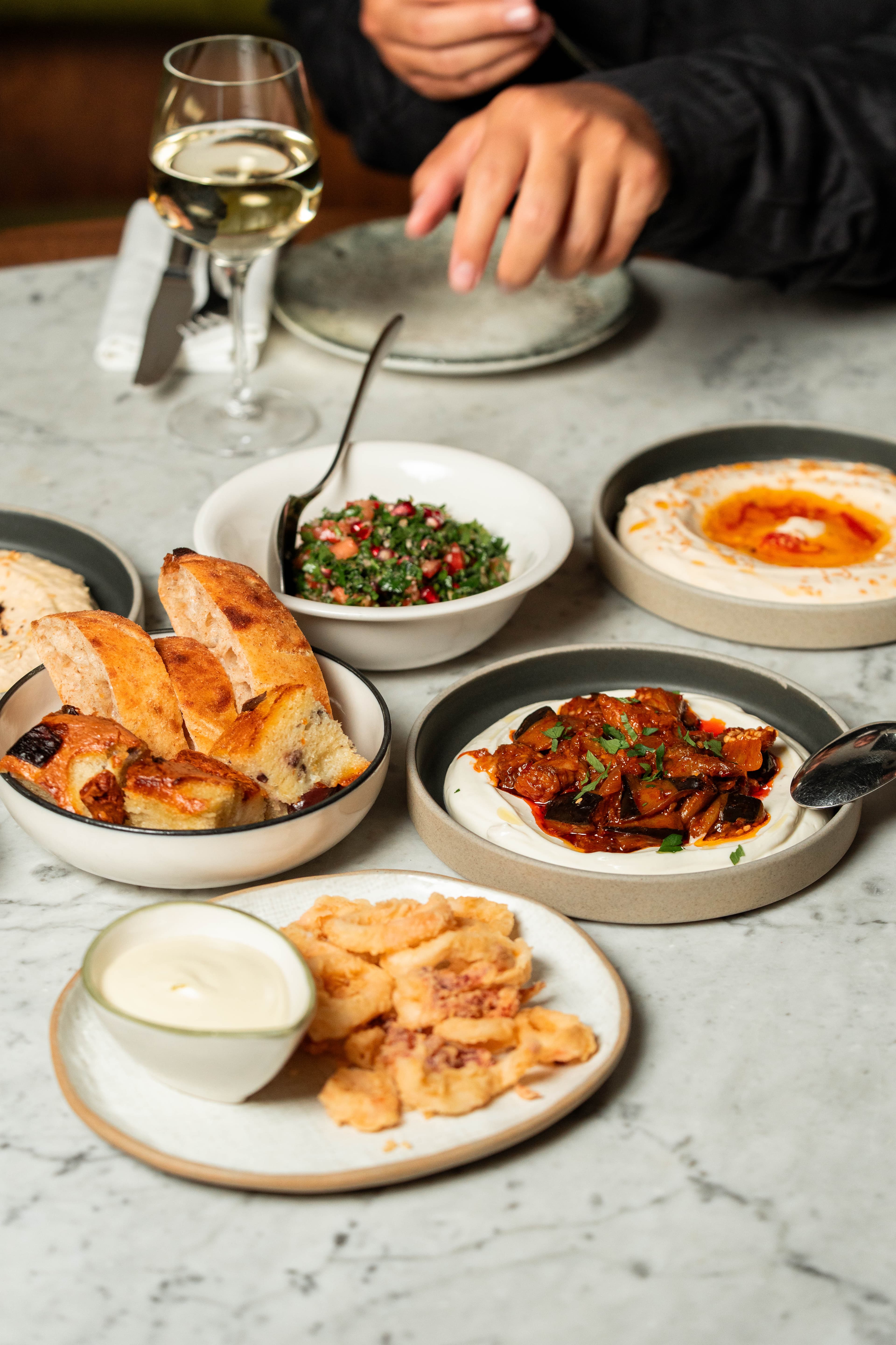 Meze of tabbouleh, hummus, aubergine, bread and fried calamari on a marble table